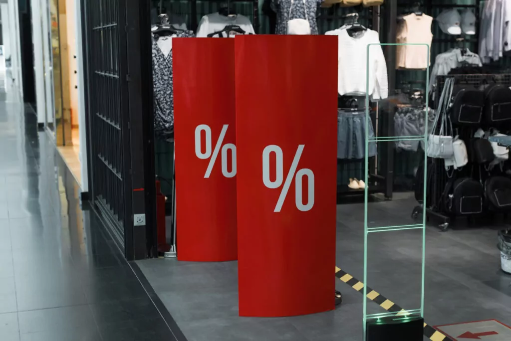 Red point-of-purchase signs with percentage symbols displayed at a clothing store entrance