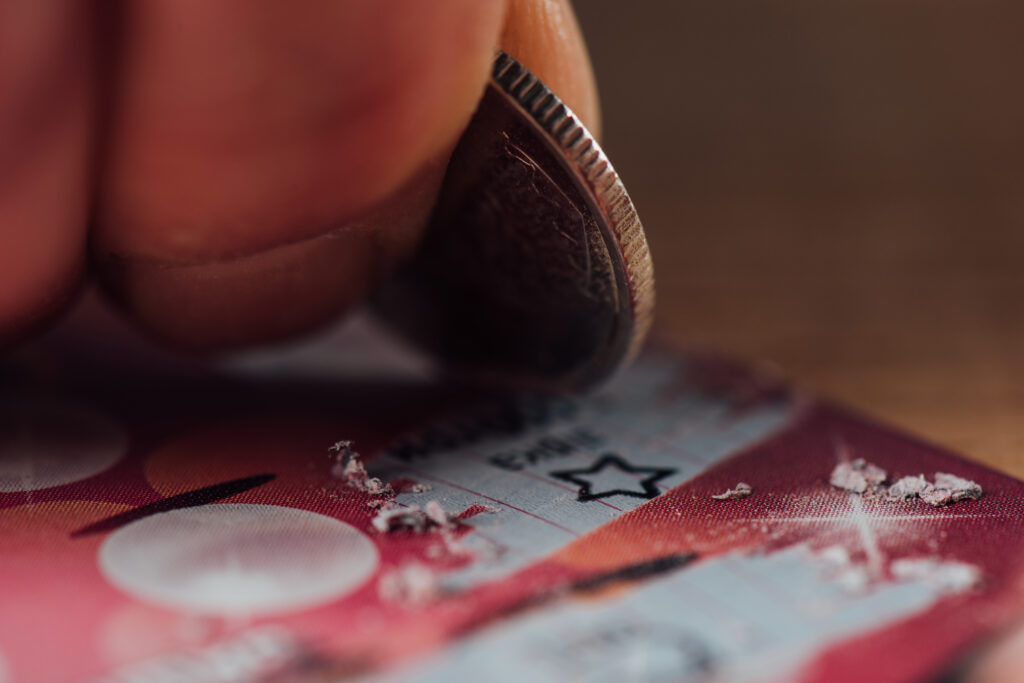 Close-up of a person using a coin to reveal a prize on a scratch off promotion card