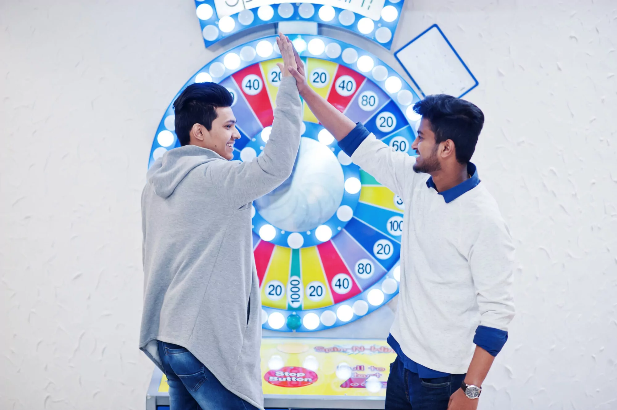 Two smiling men celebrating with a high five in front of a brightly lit Spin-to-Win game, symbolizing successful engagement and ROI.