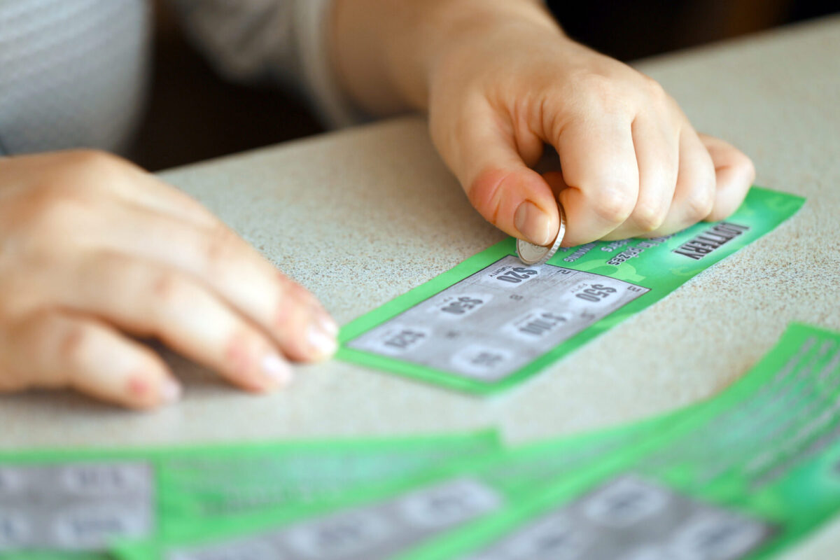 Person using a coin to scratch off a green promotional card during a scratch-off marketing campaign