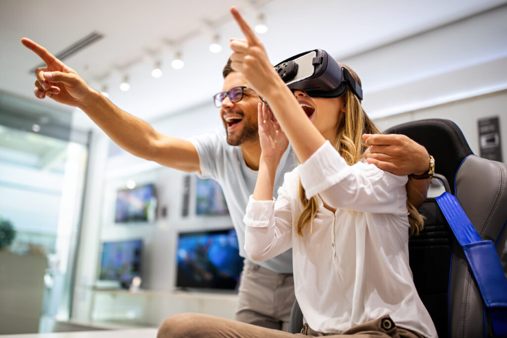 Man and woman excitedly interacting with AR product interaction game using VR headset in a bright, modern setting.