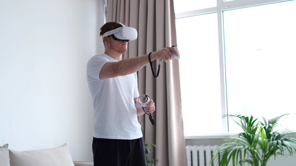 Man using a virtual reality headset and controllers in a modern living room.