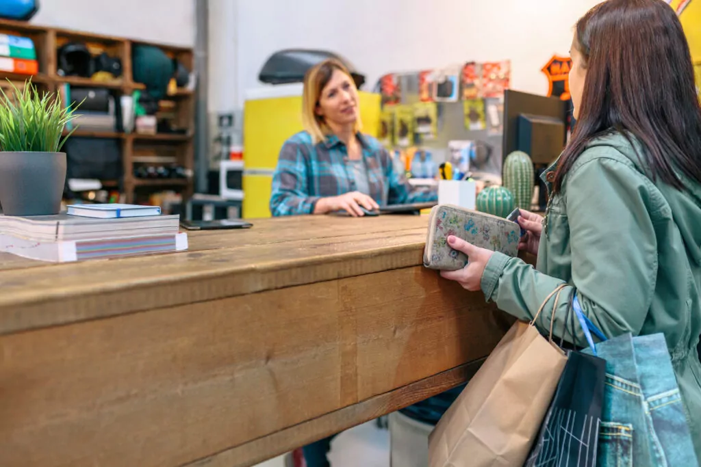 Female client purchased items on the counter while talking with woman employee on store