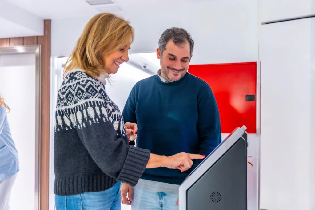 Two people interacting with an in-store kiosk, engaging with an interactive screen during a kiosk game.