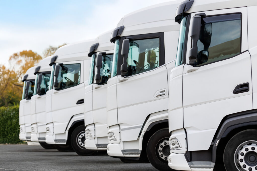 Row of white commercial trucks with flat steel doors suitable for magnetic signs
