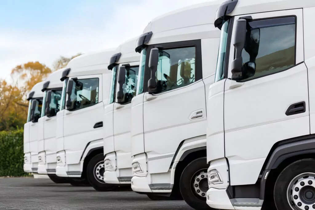 Row of white commercial trucks with flat steel doors suitable for magnetic signs