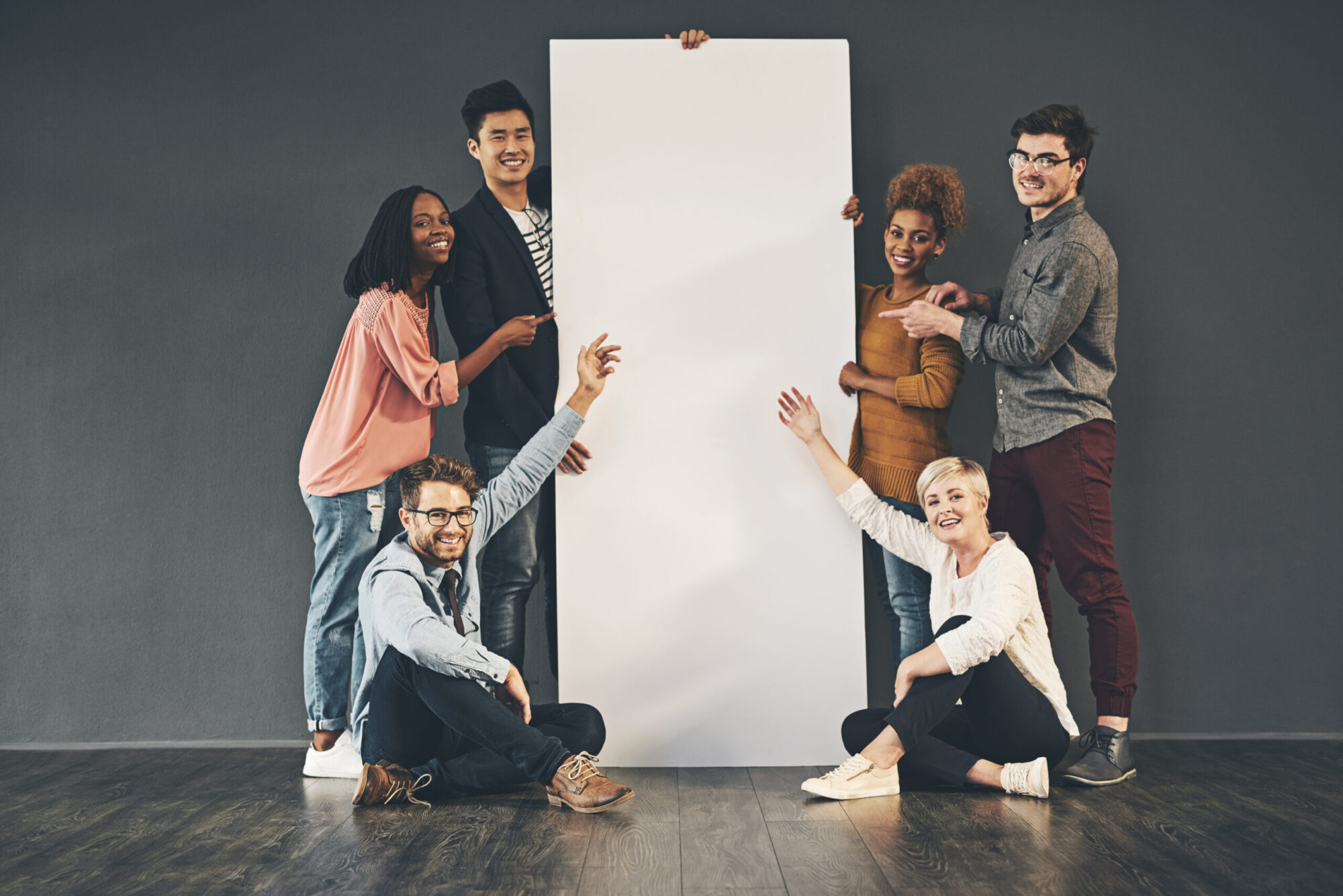 Group of six people holding a large vertical vinyl banner showing scale and size reference